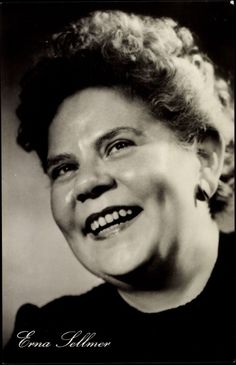 an old black and white photo of a smiling woman