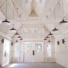 an empty room with several lights hanging from it's ceiling and two doors open