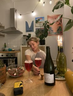 a woman sitting at a table with two wine glasses