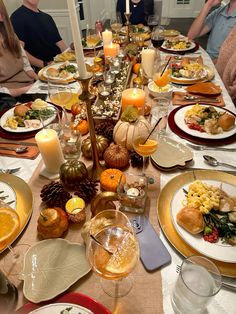 a group of people sitting around a table with plates and glasses on it, all set up for a thanksgiving dinner