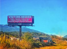 a billboard on the side of a road with mountains in the background