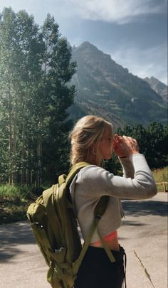 a woman walking down the street with a backpack on her back and mountains in the background