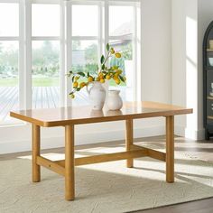 a wooden table with vases on top of it in front of a large window