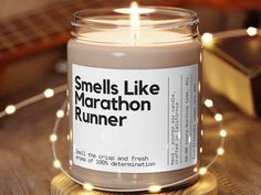 a candle that is sitting on a table with some string lights around it and the words smells like marathon runner