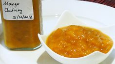 a white plate topped with a small bowl filled with sauce next to a jar of honey