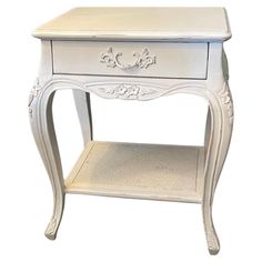 a small white table with drawers on the bottom and one drawer at the top that is open