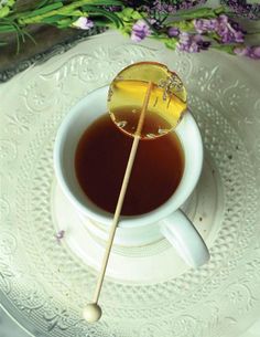 a cup of tea with a wooden stick sticking out of it and flowers in the background