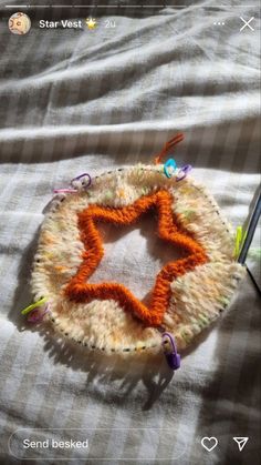 an orange and white crocheted star on a bed