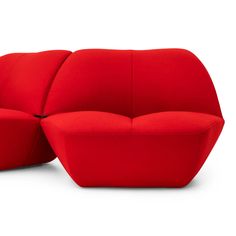 a red couch sitting on top of a white floor next to a chair and ottoman