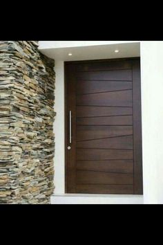 a modern wooden door in front of a stone wall