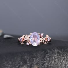 an oval shaped ring with pink stones and leaves on the band, set in gold