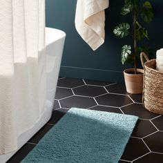 a bathroom with a blue rug and white bathtub next to a potted plant