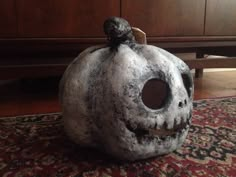 a halloween pumpkin shaped like a skull sitting on top of a rug