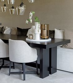 a black table with white chairs and vases on top of it next to couches