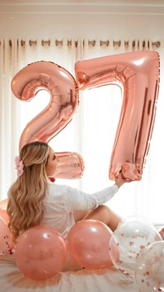 a woman sitting on top of a bed with balloons in front of her and the number twenty