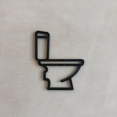 a black metal toilet symbol on a white wall