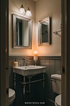 A small bathroom with a sink, mirror, candle, and toilet under warm lighting. Tranquil Decor