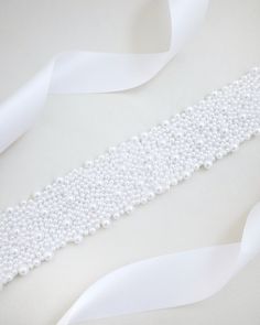 A statement sash is encrusted with beautiful pearls attached on bridal white double-faced satin ribbon. This classic pearly belts creates a romantic finishing touch to your bridal gown, bridesmaids and flower girls, or as hair accessories. DETAIL:Adult Size 108"Kids Size 78"Applique size: 12" length, 2" wideHANDMADE IN USAIMPORTED MATERIALS