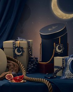 an assortment of boxes and other items on a blue table cloth with a moon in the background