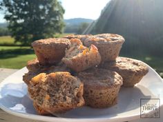 some muffins are on a white plate with grass in the background and trees