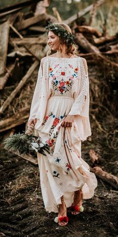 a woman in a white dress is walking through the woods with flowers on her head