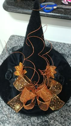 a black hat with gold sequins and bows on it sitting on a counter