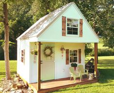 a small white house sitting on top of a lush green field