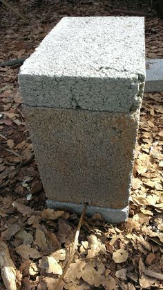 a cement block sitting on top of leaves