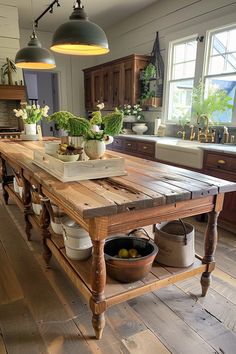 a kitchen island with potted plants on it in the middle of a wooden floor