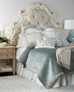 a bedroom with a white bed and blue vases on the nightstand next to it