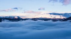 the mountains are covered in thick clouds at dusk