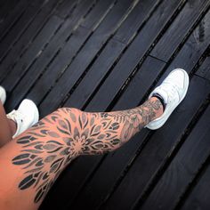 a person with tattoos sitting on a wooden floor