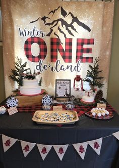 a table topped with cakes and desserts under a banner