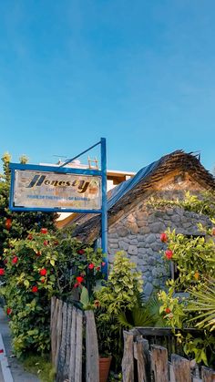 a sign that is on the side of a building with flowers in front of it