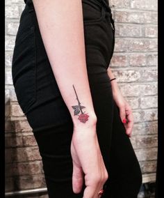 a woman with a tattoo on her arm holding a knife in one hand and a rose in the other