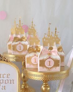 there are some little princess party favors on the cake stand with pink and gold decorations