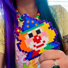 a woman with long purple hair is holding a colorful beaded piece in her hand