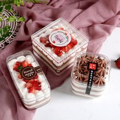 three desserts in plastic containers with strawberries and chocolate on the top one is white