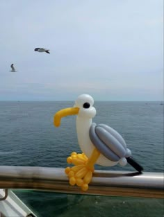 a seagull balloon sitting on top of a railing next to the ocean