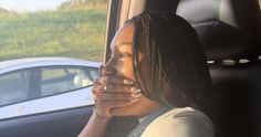 a woman sitting in the back seat of a car with her hand on her face