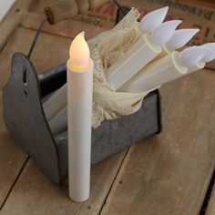 a white candle sitting on top of a wooden table next to an old fashioned box