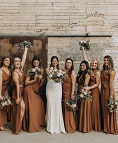 a group of women standing next to each other holding bouquets in front of a brick wall