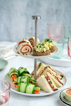 a three tiered plate with sandwiches and vegetables