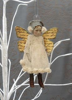 an angel ornament hanging on a tree branch with white branches in the background