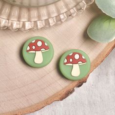 two mushroom buttons sitting on top of a piece of wood next to a green plant