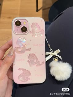 someone is holding their phone case with some charms on it