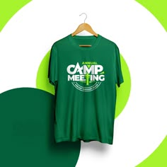 a green t - shirt with the words camp meeting on it hanging from a hanger