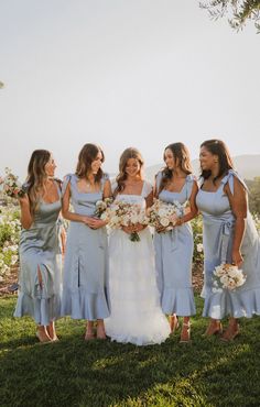 the bride and her bridesmaids are all dressed in light blue dresses with matching bouquets