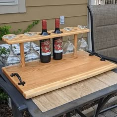 three bottles of wine sit on a wooden serving tray that is attached to an outdoor table