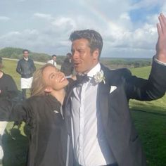 a man and woman standing in front of a rainbow